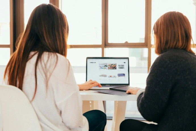 Deux femmes parlant stratégie digitale devant un ordinateur