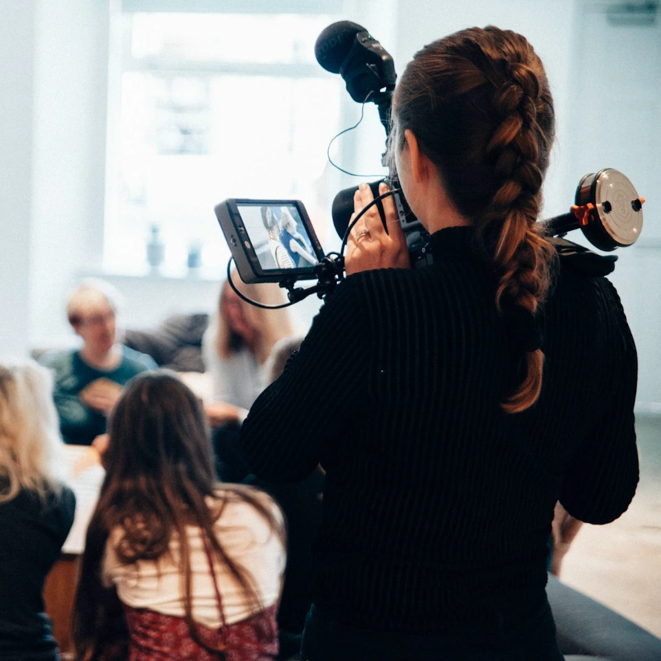 woman holding camera standing near people