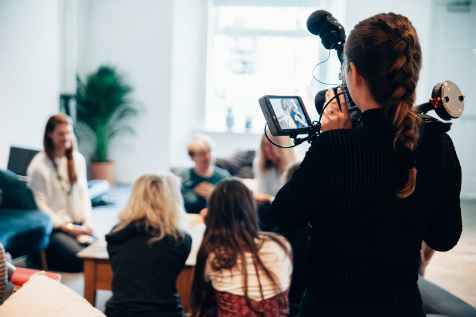 Femme vidéaste filmant un groupe de personnes