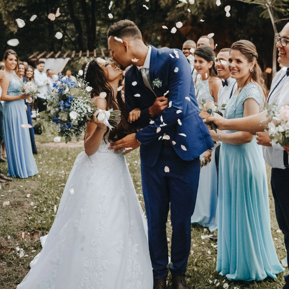 Mariés s'embrassant accompagnés de leurs familles et amis