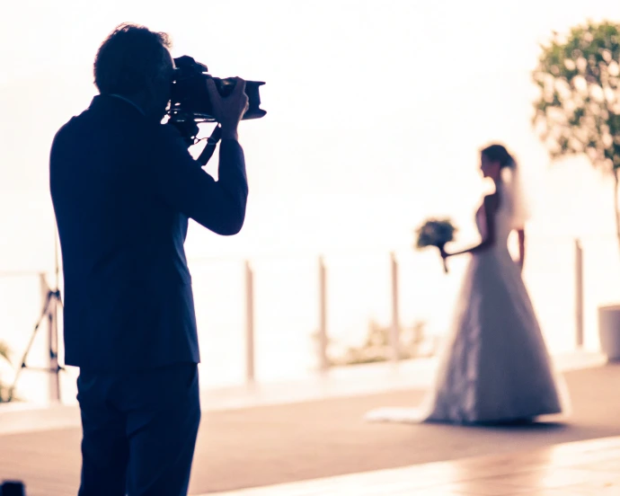 Vidéaste de mariage filmant une mariée en contre-jour, illustrant la maîtrise de la lumière naturelle en vidéo