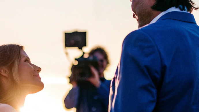 Vidéaste filmant un couple lors de leur mariage, captant la continuité et les émotions de la journée